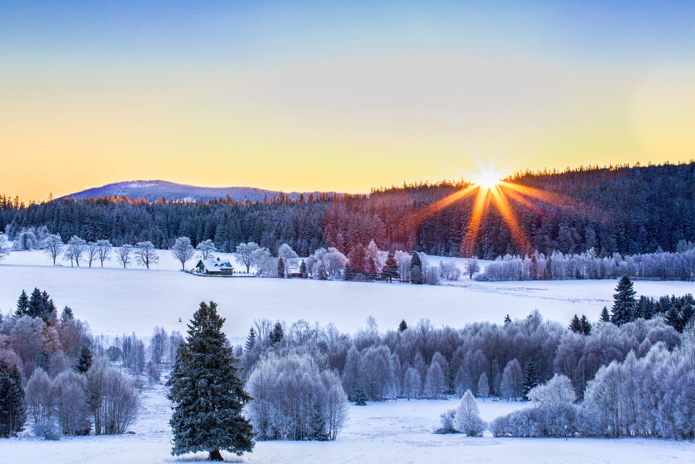 Východ slunce nad idylickou zasněženou krajinou